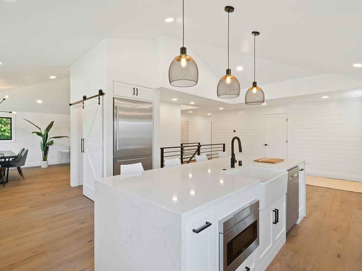 Modern farmhouse kitchen with white quartz island, pendant lights, and shiplap walls — finished rehab