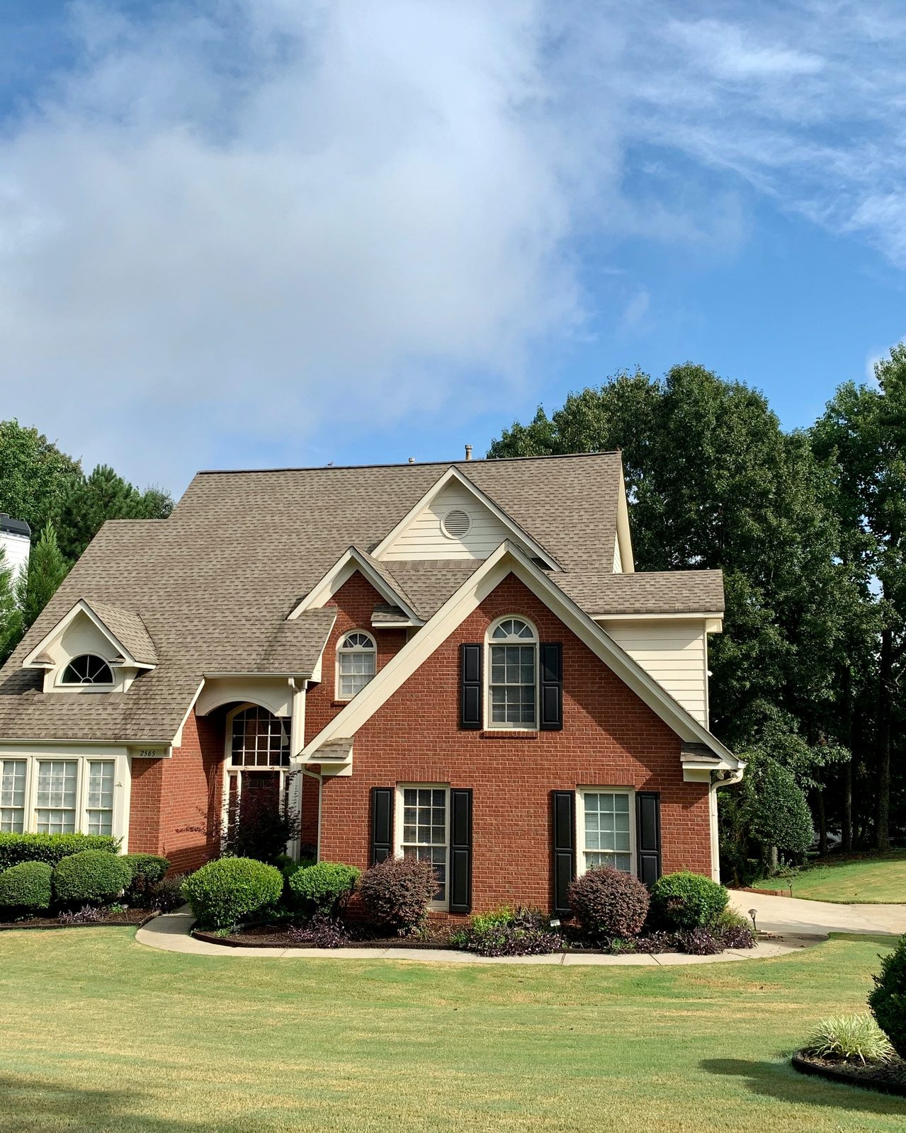 Restored Southeastern brick single-family home with manicured landscaping and dramatic sky