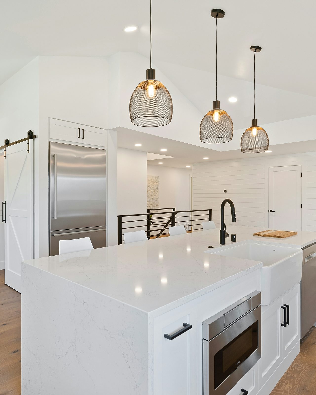 Modern farmhouse kitchen with white quartz island, pendant lights, and shiplap walls — finished rehab